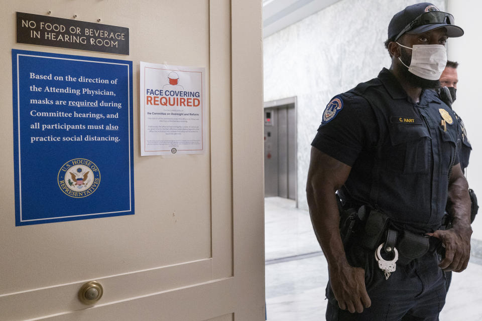 Capitol Police officers wear face masks by a signs stating that face coverings and social distancing are required, outside a House Committee on Oversight and Reform hearing, Thursday, July 29, 2021, on Capitol Hill in Washington. (AP Photo/Jacquelyn Martin)