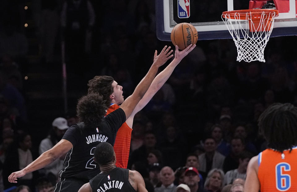 Oklahoma City Thunder guard Josh Giddey, rear, is fouled by Brooklyn Nets forward Cameron Johnson (2) as he goes to the basket during the first half of an NBA basketball game Tuesday, March 14, 2023, in Oklahoma City. (AP Photo/Sue Ogrocki)