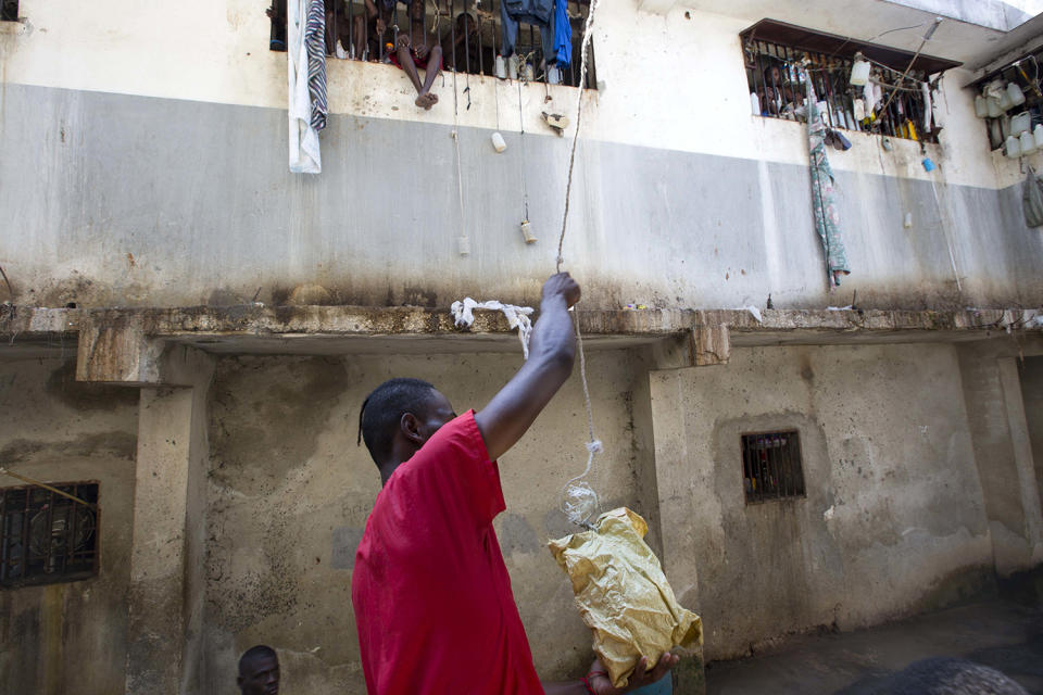 <p>A prisoner puts food in a bag to send up to a fellow inmate at the National Penitentiary in downtown Port-au-Prince, Haiti, Feb. 13, 2017. Prison authorities say they try their best to meet inmates’ needs, but repeatedly receive insufficient funds from the state to buy food and cooking fuel. Some inmates are provided meals by visiting relatives and others are permitted by guards to meet with contacts to bring in food, cigarettes and other things. (Photo: Dieu Nalio Chery/AP) </p>
