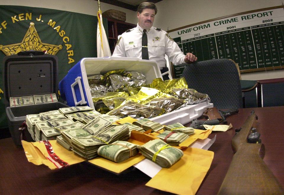 St. Lucie County Sheriff Ken Mascara stands over 14 of 30 pounds of hydroponic marijuana, $240,000.00 in cash and three weapons confiscated from a Friday, Sept. 12, 2003, drug arrest in the Tanglewood Mobile Home Park in Fort Pierce. Mascara believed in communicating well with the media and his community, according to Mark Weinberg, the sheriff's former public information officer.