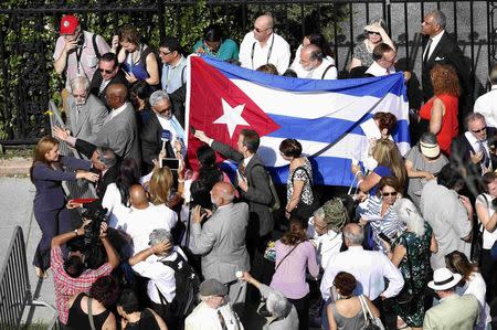People carry the Cuban flag outside the Cuban Embassy before it reopened with an official ceremony in Washington July 20, 2015. REUTERS/Gary Cameron