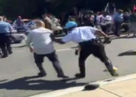 FILE PHOTO: A Police officer pushes a man away from protesters, in this still image captured from a video footage, during a violent clash outside the Turkish ambassador's residence between protesters and Turkish security personnel during Turkish President Tayyip Erdogan's visit to Washington, DC, U.S. on May 16, 2017. Courtesy Armenian National Committee of America/Handout via REUTERS