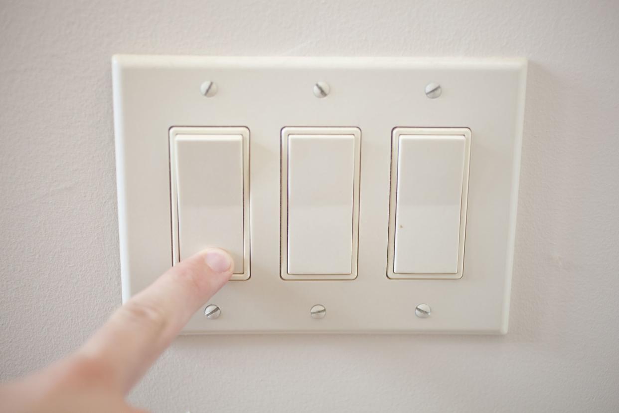 finger turning off light switch on wall