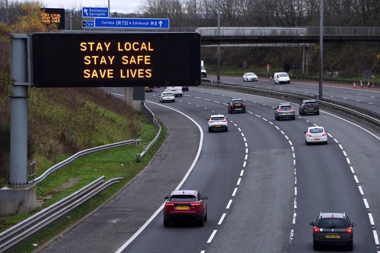 Cars pass a Covid warning sign on the eastbound M8 motorway in Glasgow ahead of the introduction of further coronavirus restrictions on November 20, 2020. - Swathes of western and central Scotland prepared to enter a three-week period of restrictions this evening. From 6:00 pm (1800 GMT) non-essential shops, hospitality, gyms and beauty salons will shut in 11 council areas including the most populous city of Glasgow. (Photo by Andy Buchanan / AFP) (Photo by ANDY BUCHANAN/AFP via Getty Images)