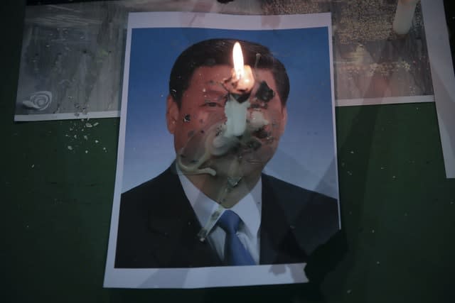A candle burns on a photo of Chinese President Xi Jinping (Kin Cheung/AP)
