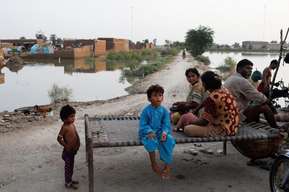 Flood victims, a family, sit along a street with the submerged houses in the background, following rains and floods during the monsoon season in Mehar, Pakistan August 29, 2022.