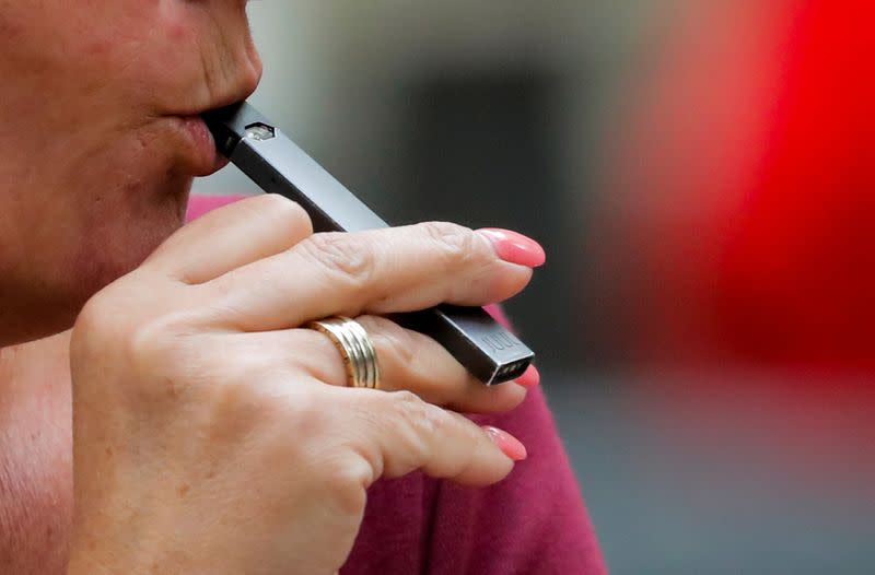 FILE PHOTO: A woman smokes a Juul e-cigarette in New York