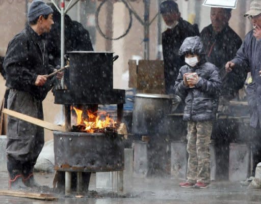 A boy (R) waits for boiled water to cook instant noodles outside a shelter in Sendai, in Miyagi prefecture. Japanese crews grappling with the world's worst nuclear incident since Chernobyl temporarily pulled out Wednesday as radiation rose following feared damage to a reactor containment vessel