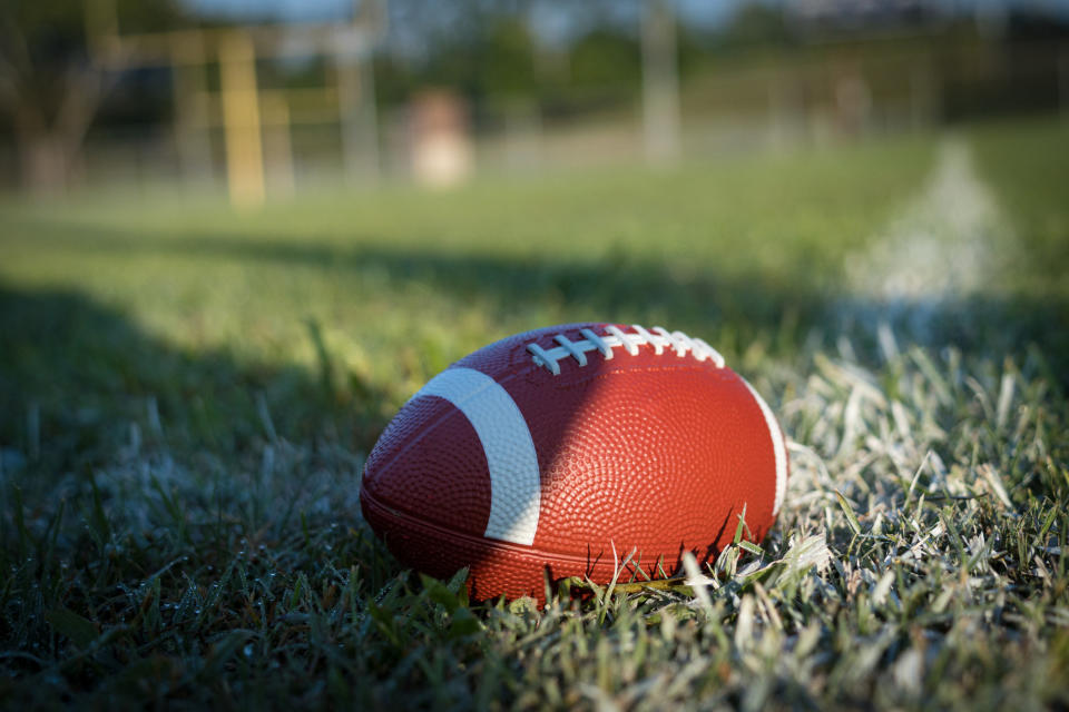 Football on grass field with white boundary line in background