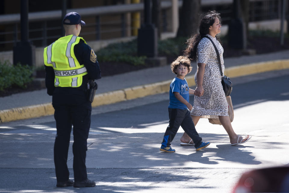 A young boy looks at a Virginia State Police officer as he is escorted away from the Tysons Corner Center mall, following a shooting inside the shopping center, in Tysons Corner, Va., Saturday, June 18, 2022. (AP Photo/Cliff Owen)