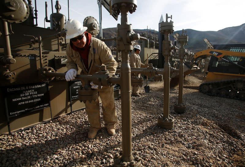FILE PHOTO: Workers put the final touches on a natural gas well platform owned by Encana south of Parachute, Colorado
