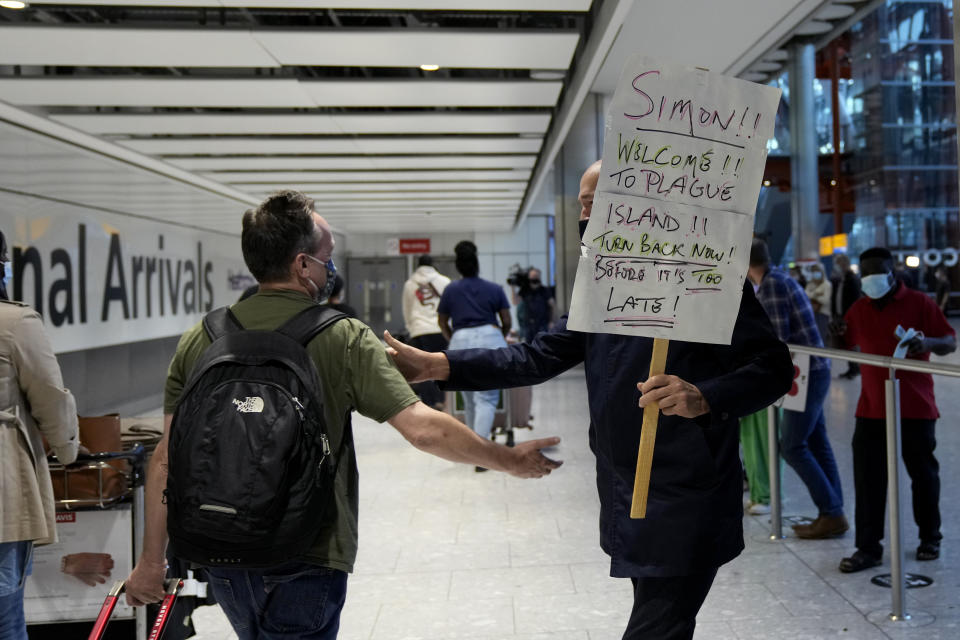 A man holds a sign as he greets his brother arriving on a flight at Terminal 5 of Heathrow Airport in London, Monday, Aug. 2, 2021. Travelers fully vaccinated against coronavirus from the United States and much of Europe were able to enter Britain without quarantining starting today, a move welcomed by Britain's ailing travel industry. (AP Photo/Matt Dunham)