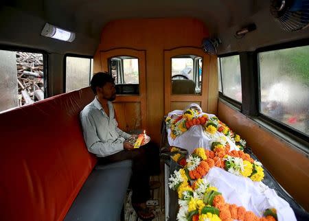 A relative sits inside an ambulance with the body of a victim who died after consuming bootleg liquor at a cremation ground in Mumbai, June 20, 2015. REUTERS/Danish Siddiqui