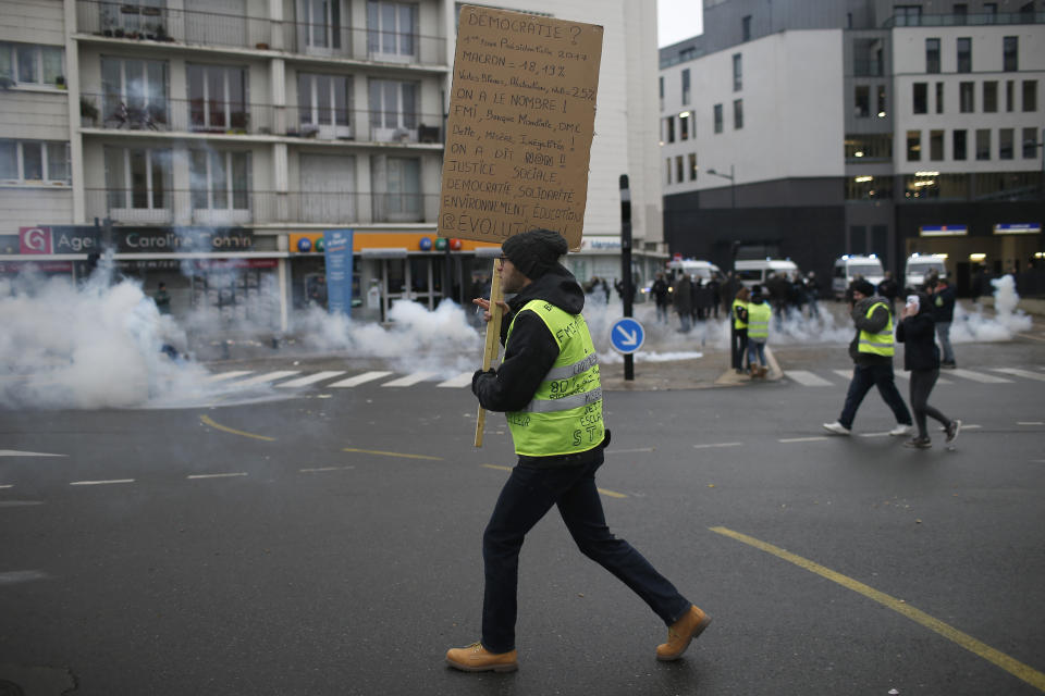 A yellow vest protestor holds a placard during clashes in Bourges, central France, Saturday, Jan. 12, 2019. Paris brought in armored vehicles and the central French city of Bourges shuttered shops to brace for new yellow vest protests. The movement is seeking new arenas and new momentum for its weekly demonstrations. Authorities deployed 80,000 security forces nationwide for a ninth straight weekend of anti-government protests. (AP Photo/Rafael Yaghobzadeh)