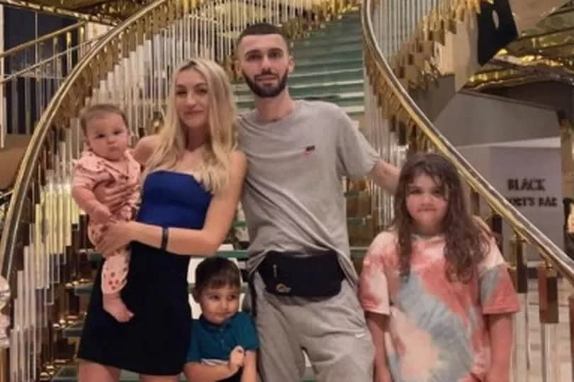 Holly and her partner and three children standing at the bottom of a staircase in the hotel