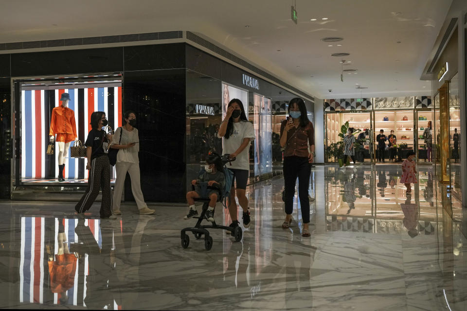 Residents wearing face masks tour past reopened retail shops inside a mall that was closed due to COVID-19 restrictions in Beijing, Sunday, May 29, 2022. (AP Photo/Andy Wong)