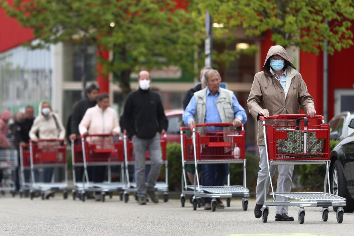 People wearing protective masks queue up to go in a garden store in Munich, Germany, on Monday, April 20, 2020. The German government has moved to restrict freedom of movement for people, in an effort to slow the onset of the COVID-19 coronavirus.