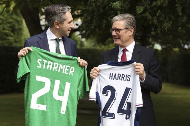 Taoiseach Simon Harris and Prime Minister Sir Keir Starmer hold up their respective national football teams' shirts, with their names on their opposite teams' shirts, at Farmleigh House