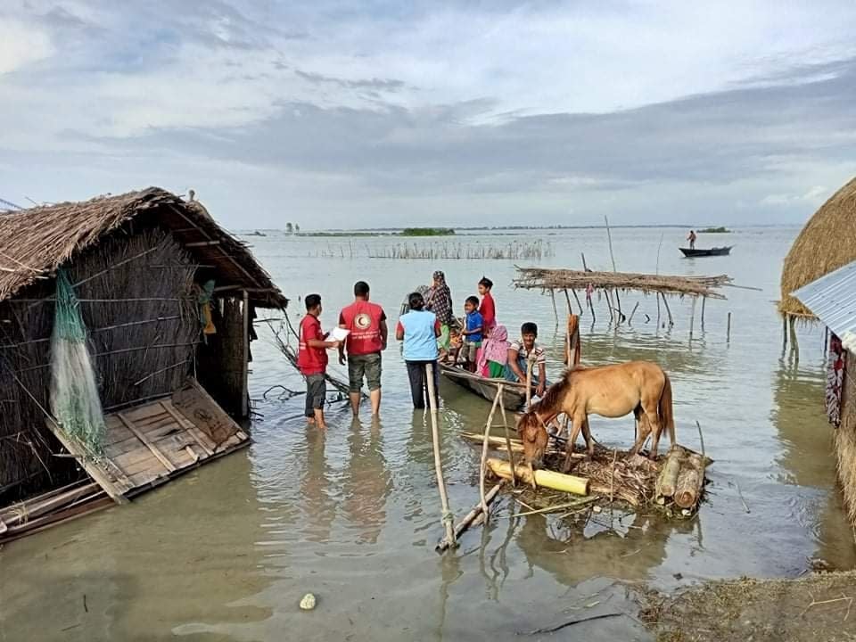 In this photograph provided by International Federation of Red Cross and Red Crescent Societies (IFRC) shows IFRC volunteers reaching flood affected communities with drinking water and other support in Kurigram, Bangladesh, July 16, 2020. More than 9.6 million people across South Asia have been affected by severe floods, with hundreds of thousands struggling to get food and medicine, officials and aid organizations said Wednesday. (IFRC via AP)