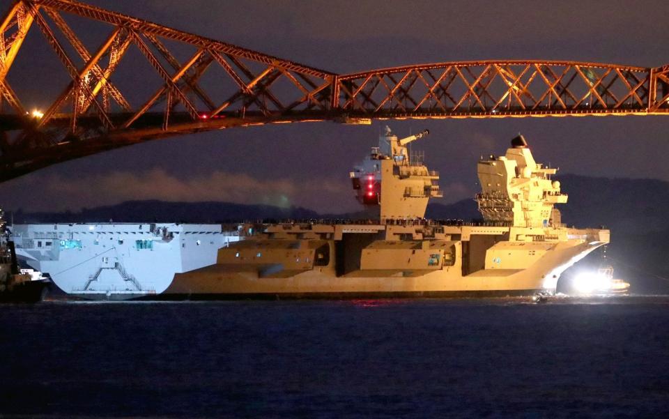 HMS Queen Elizabeth is pulled by tugs under the Forth Rail Bridge - Credit: Jane Barlow/PA