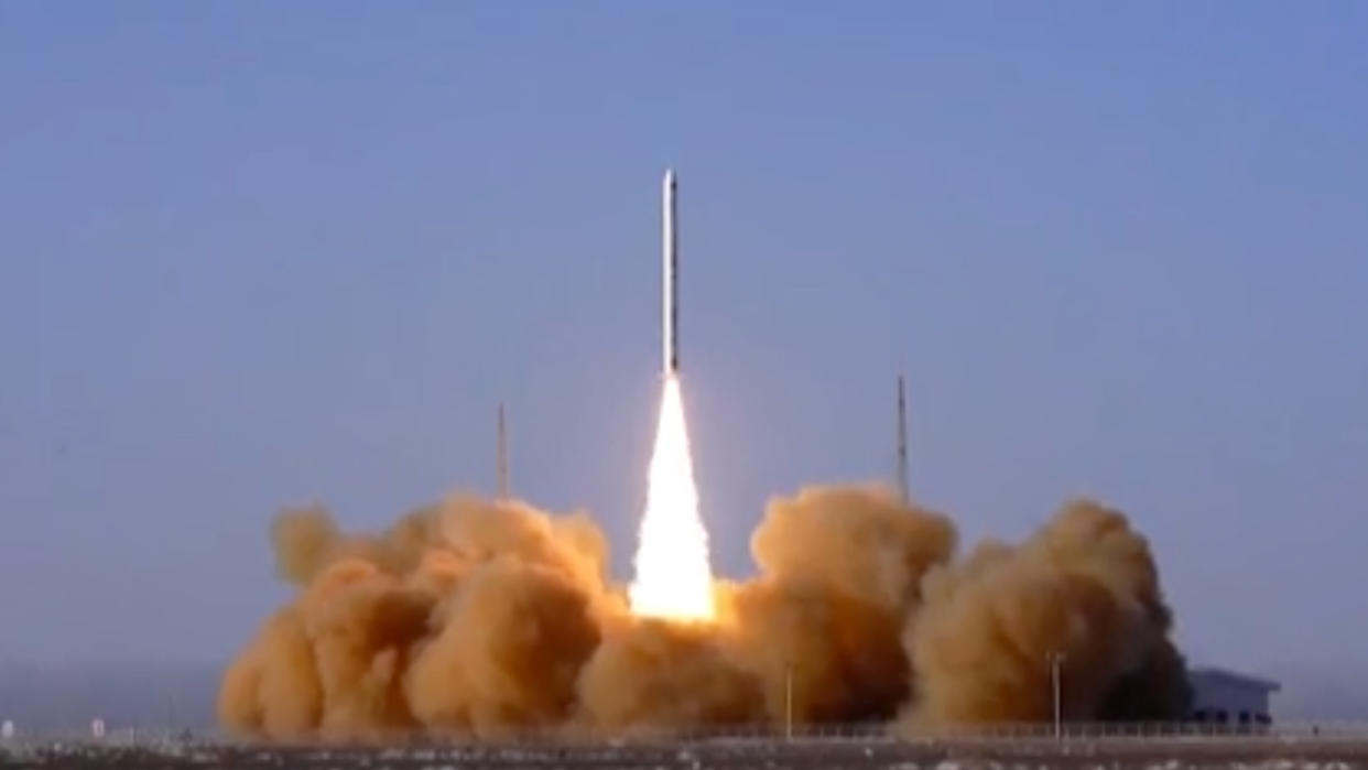  A white rocket launches into a blue sky. 