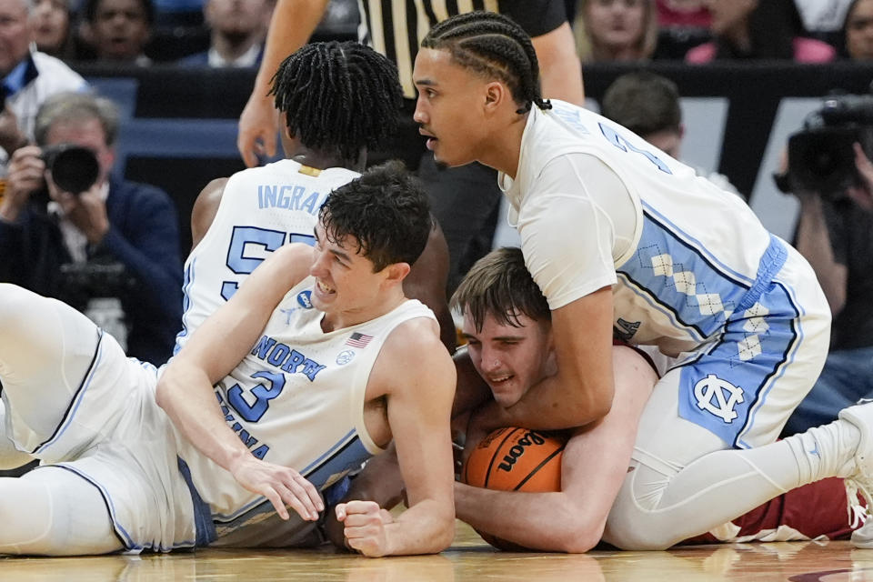 Alabama forward Grant Nelson, center, reaches for a loose ball between North Carolina guard Cormac Ryan (3) and guard Seth Trimble (7) during the second half of a Sweet 16 college basketball game in the NCAA tournament Thursday, March 28, 2024, in Los Angeles. (AP Photo/Ryan Sun)