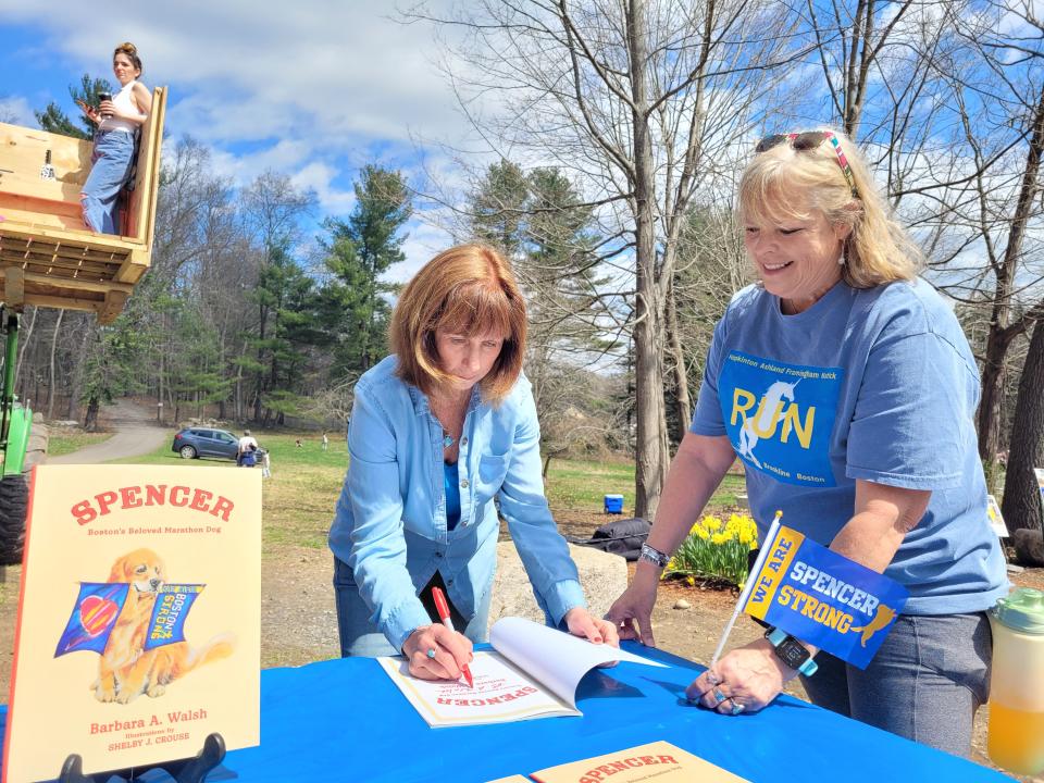 Author and journalist Barbara Walsh signs a copy of her book, "Spencer: Boston's Beloved Marathon Dog," for Pam Morgan, of Alpharetta, Georgia.