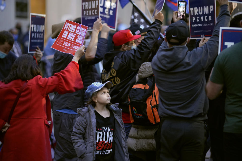 A young child watches as supporters of President Donald Trump hold signs while they demonstrate outside the Pennsylvania Convention Center where votes are being counted, Thursday, Nov. 5, 2020, in Philadelphia, following Tuesday's election. (AP Photo/Matt Slocum)