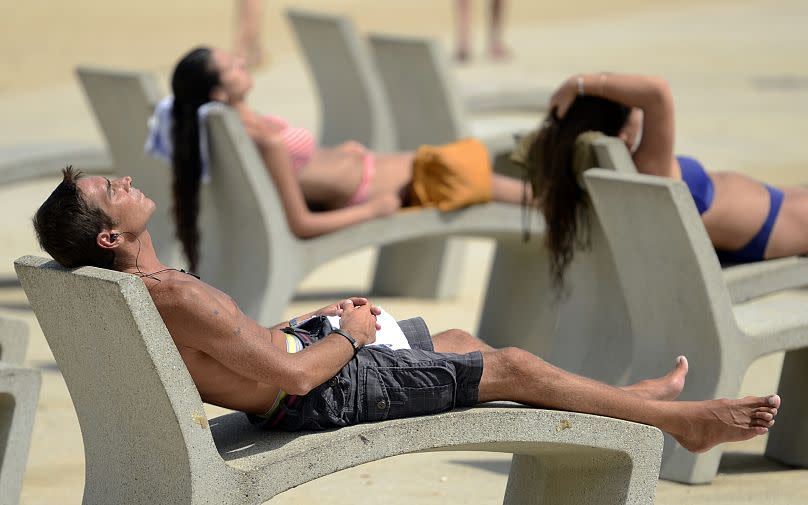 Personas tomando el sol en la playa.