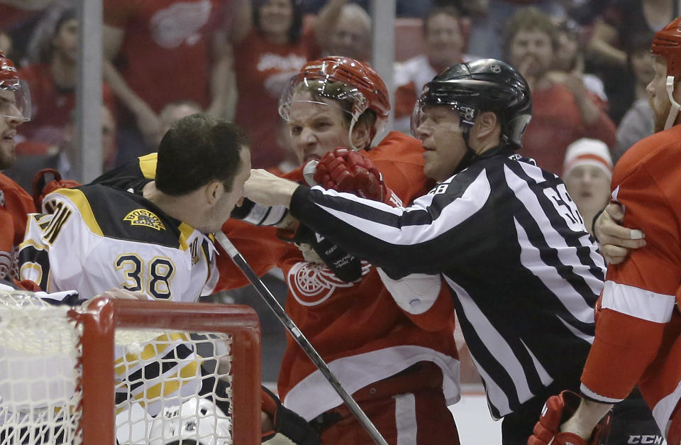 A referee breaks up Boston Bruins left wing Jordan Caron (38) and Detroit Red Wings left wing Justin Abdelkader during the first period of Game 3 of a first-round NHL hockey playoff series in Detroit, Tuesday, April 22, 2014. (AP Photo/Carlos Osorio)