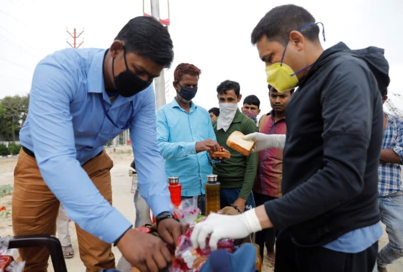 Local residents offer food to the migrant workers who are returning to their villages, after India ordered a 21-day nationwide lockdown to limit the spreading of coronavirus disease (COVID-19), in Ghaziabad