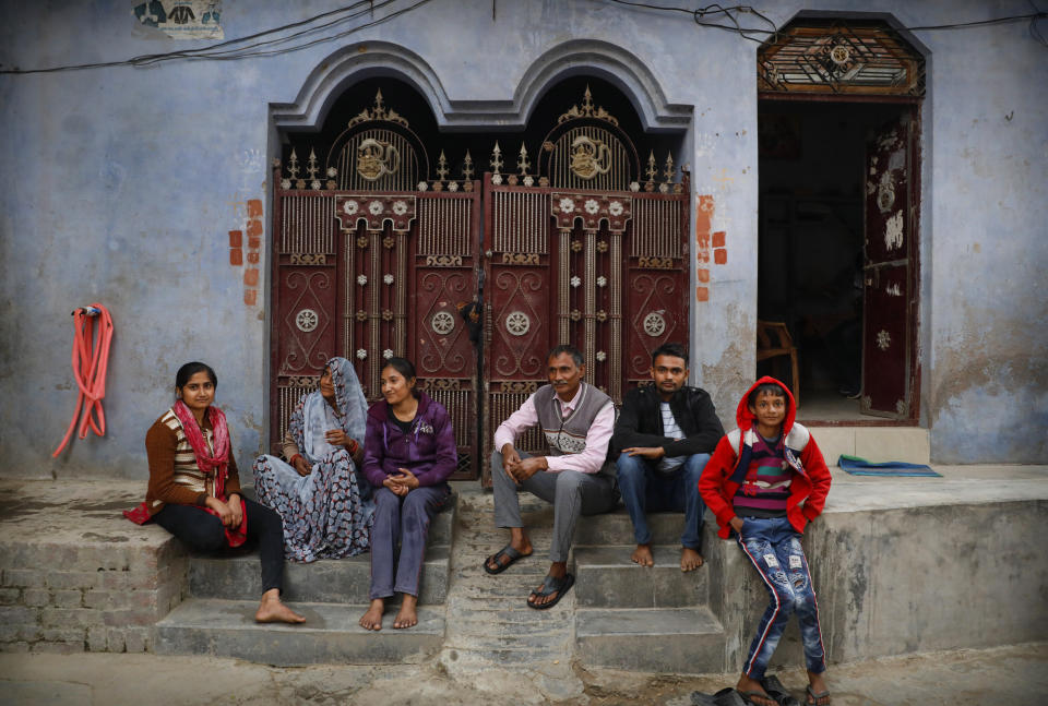 Indian farmer Ram Singh Patel, third right, poses for a photograph with his wife Kantee Devi, second left, and children Anuradha Patel, left, Asmita Patel, third left, Shubham Patel, second right, and Shivansh Patel outside their village house in Fatehpur district, 180 kilometers (112 miles) south of Lucknow, India, Saturday, Dec. 19, 2020. Patel's day starts at 6 in the morning, when he walks into his farmland tucked next to a railway line. For hours he toils on the farm, where he grows chili peppers, onions, garlic, tomatoes and papayas. Sometimes his wife, two sons and two daughters join him to lend a helping hand or have lunch with him. (AP Photo/Rajesh Kumar Singh)