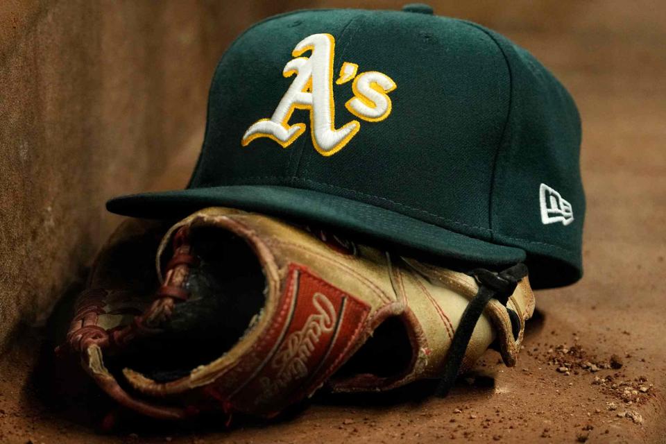 <p>Sam Hodde/Getty</p> A close up view of an Oakland Athletics hat and Rawlings glove during the game against the Texas Rangers at Globe Life Field on April 21, 2023 in Arlington, Texas