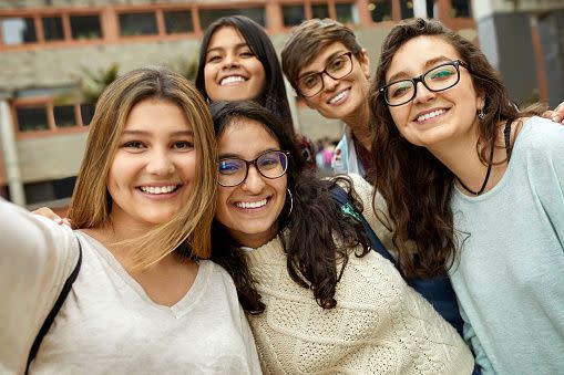 Group of friends take selfie on college campus.