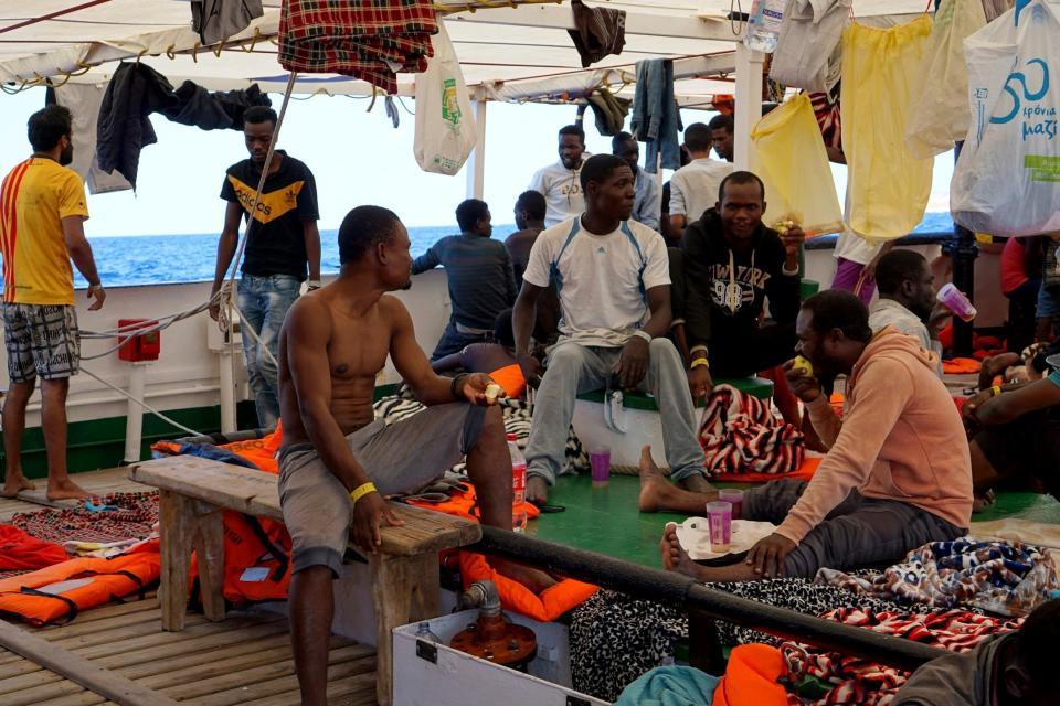 Migrants sit on the deck of the Open Arms vessel in front of island of Lampedusa. (AP)