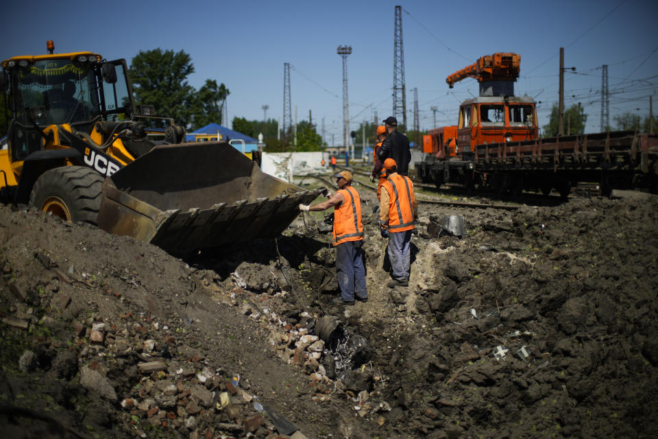 Workers remove pieces of a rocket from a crater after a Russian strike in Pokrovsk, eastern Ukraine, Wednesday, May 25, 2022. Two rockets struck the eastern Ukrainian town of Pokrovsk, in the Donetsk region early Wednesday morning, causing at least four injuries. (AP Photo/Francisco Seco)