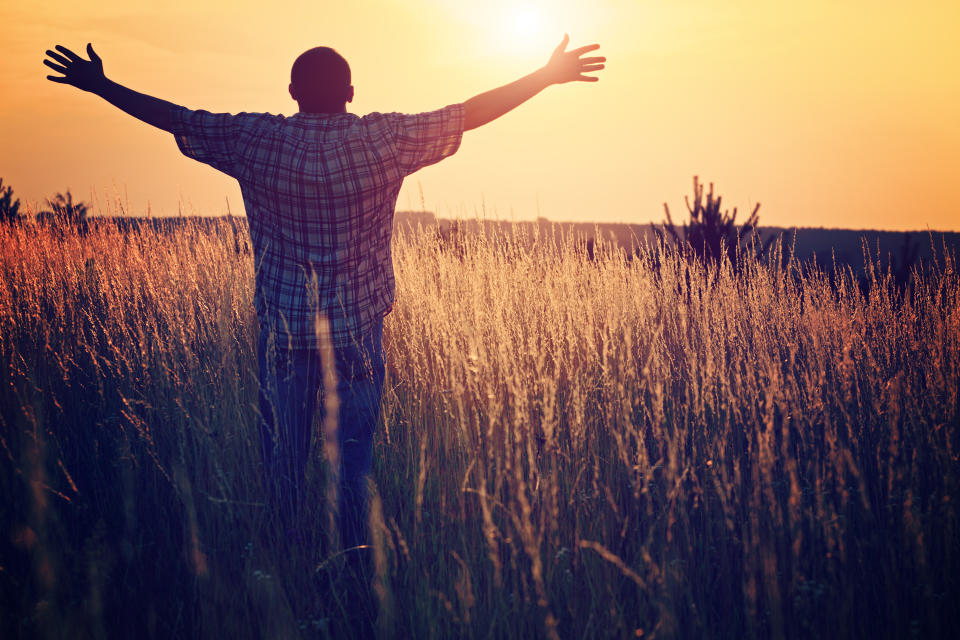 Un hombre levanta los brazos hacia el cielo, con el rostro vuelto hacia el sol. (Foto: Getty)
