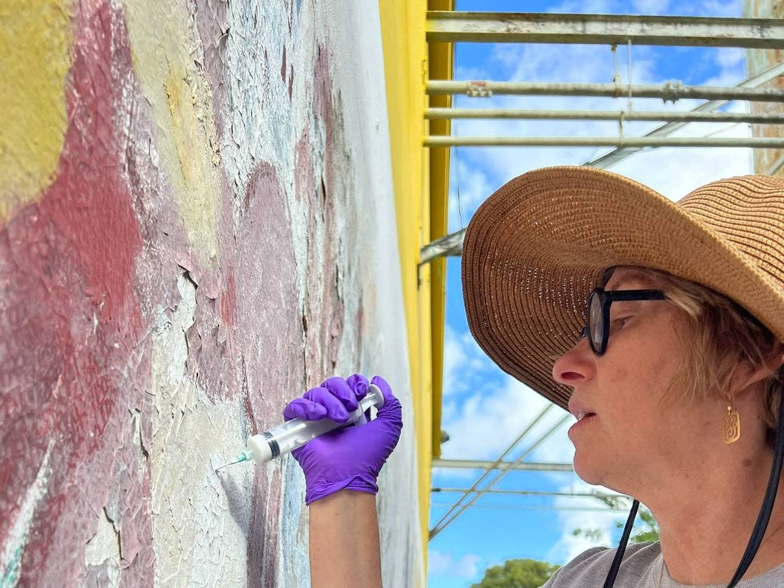 Conservator Rosa Lowinger working to preserve a mural by Miami artist Purvis Young. The mural was faded and mold was living underneath the paint.