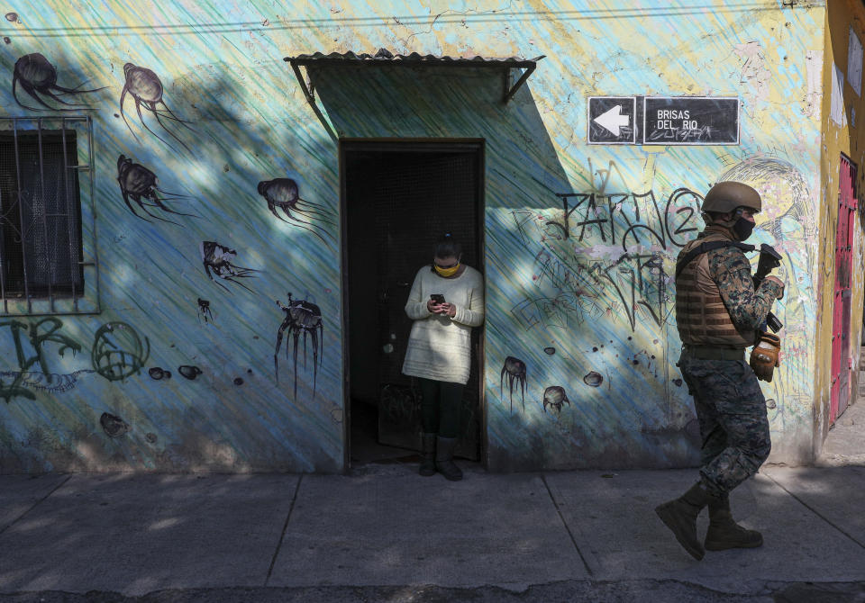 Un soldado se desplaza mientras un residente espera a que los trabajadores de la municipalidad entreguen una caja de alimentos durante una cuarentena obligatoria ordenada por el gobierno en medio de la pandemia de coronavirus en Santiago de Chile, el viernes 22 de mayo de 2020. (Foto AP/ Esteban Félix)