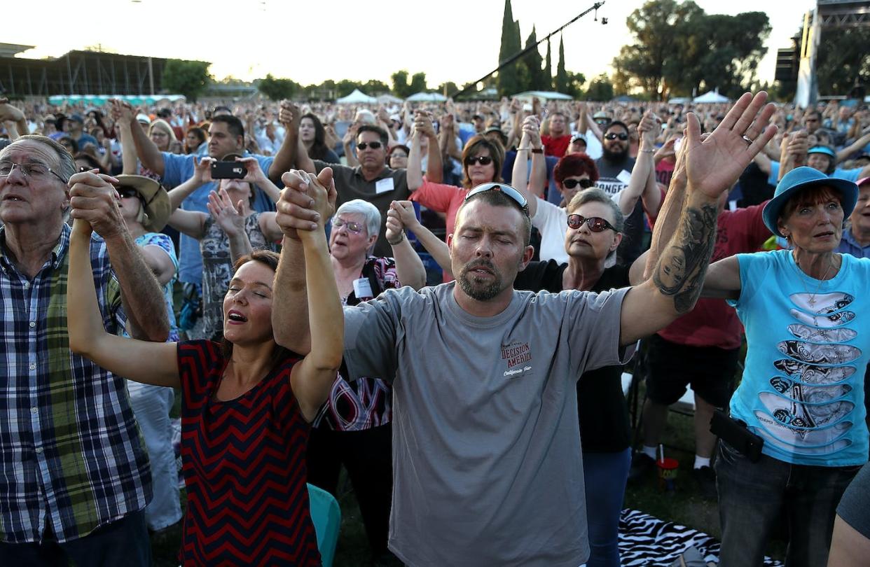 Attendees at evangelist Franklin Graham's 'Decision America' tour in Turlock, Calif., in 2018. The tour was to encourage Christians to vote. <a href="https://www.gettyimages.com/detail/news-photo/attendees-hold-hands-and-pray-as-rev-franklin-graham-speaks-news-photo/963640408?adppopup=true" rel="nofollow noopener" target="_blank" data-ylk="slk:Justin Sullivan/Getty Images;elm:context_link;itc:0;sec:content-canvas" class="link ">Justin Sullivan/Getty Images</a>