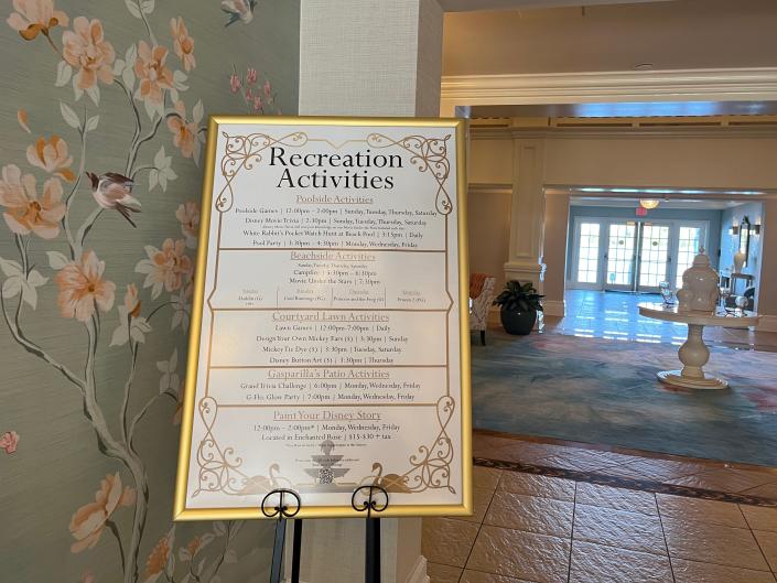 a large sign listing recreational activities at the grand floridian leaning against a wallpapered wall