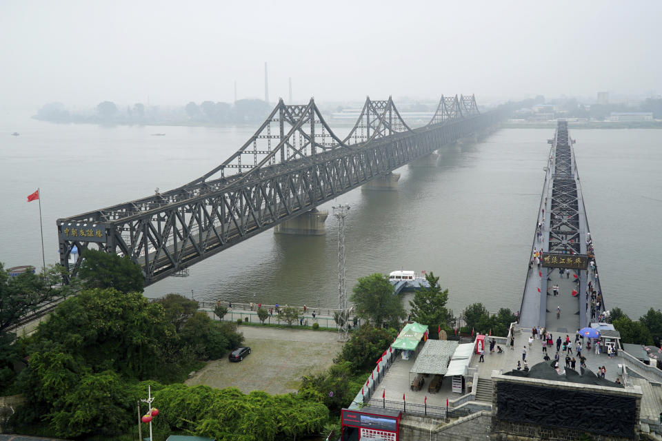 FILE - In this Sept. 9, 2017, file photo, visitors walk across the Yalu River Broken Bridge, right, next to the Friendship Bridge connecting China and North Korea in Dandong in northeastern China's Liaoning province. North Korea banned foreign tourists to guard against the spread of a new virus from China, a tour operator said. The temporary closing of the North Korean border would begin Wednesday, Jan. 22, 2020. (AP Photo/Emily Wang, File)