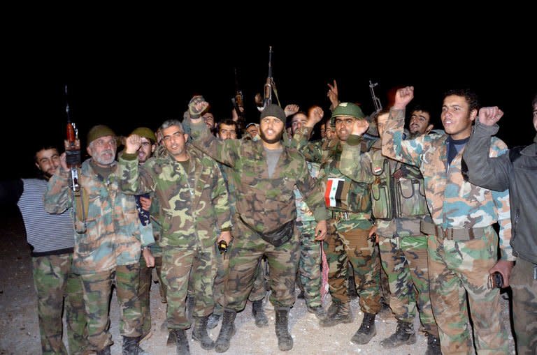 Pro-government forces celebrate their alleged victory in a battle against rebels at the Air Defence Base in Tal Hassil, 15 kms from Aleppo Airport, on December 30, 2012. Violence ravaged Syria into 2013 with the gruesome discovery of dozens of tortured, headless corpses in a Damascus district, clouding end-of-year efforts by peace envoy Lakhdar Brahimi to end 21 months of bloodshed