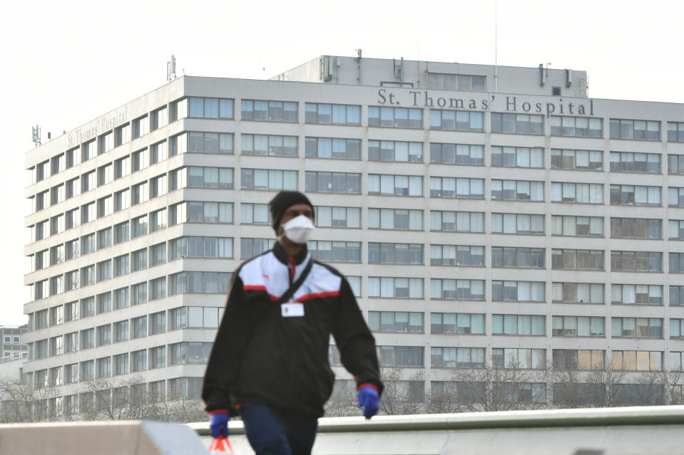 A man wearing a face mask walks near St Thomas' Hospital in Central London, where Prime Minister Boris Johnson remains in intensive care as his coronavirus symptoms persist. (Photo by Dominic Lipinski/PA Images via Getty Images)