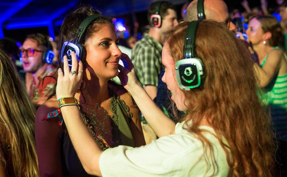 Savanna Erickson helps her friend Mikayla Jovanovich adjust her wireless headphones at ACL Fest's Silent Disco in 2017.  Fans who aren't feeling the music on the ACL stages can end their nights dancing to DJs in the Tito's tent.