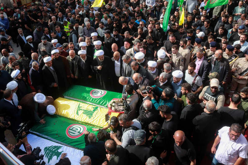 Lebanese mourners carry flags-draped coffins of four people, who were killed in an overnight Israeli in the southern Lebanese village of Naqoura, during their funeral procession. STR/dpa
