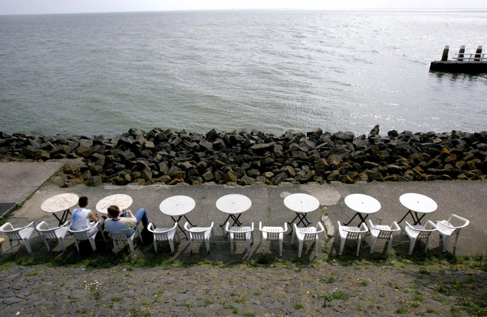 In this image taken Thursday Sept. 1, 2005, Tourists enjoy a bit of sun as they sit on Afsluitdijk, one of the dikes protecting the Dutch heartland, near the north western town of Den Oever, Netherlands. Rising in a thin line through the surface of waters separating the provinces of North Holland and Friesland, the 87-year-old Afsluitdijk is one of the low-lying Netherlands' key defenses against the sea. With climate change bringing more powerful storms and rising sea levels, it's getting a major makeover. (AP Photo/Peter Dejong)