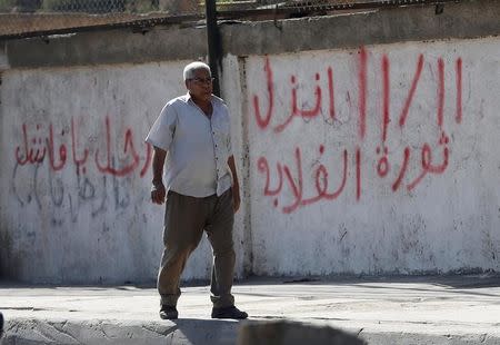 A man walks in front of a wall with graffiti asking Egyptians to participate in demonstrations against the Egyptian regime and against economic conditions following the rise of prices around the country, in Cairo, Egypt November 9, 2016. The words read, "11/11 Revolutions of Ghalaba (Marginalised) or poor people, Leave ya Sisi you are unstuck". REUTERS/Amr Abdallah Dalsh