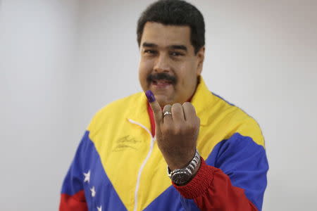 Venezuela's President Nicolas Maduro shows his ink-stained finger after voting in a polling center in Caracas, June 28, 2015. REUTERS/Jorge Dan Lopez