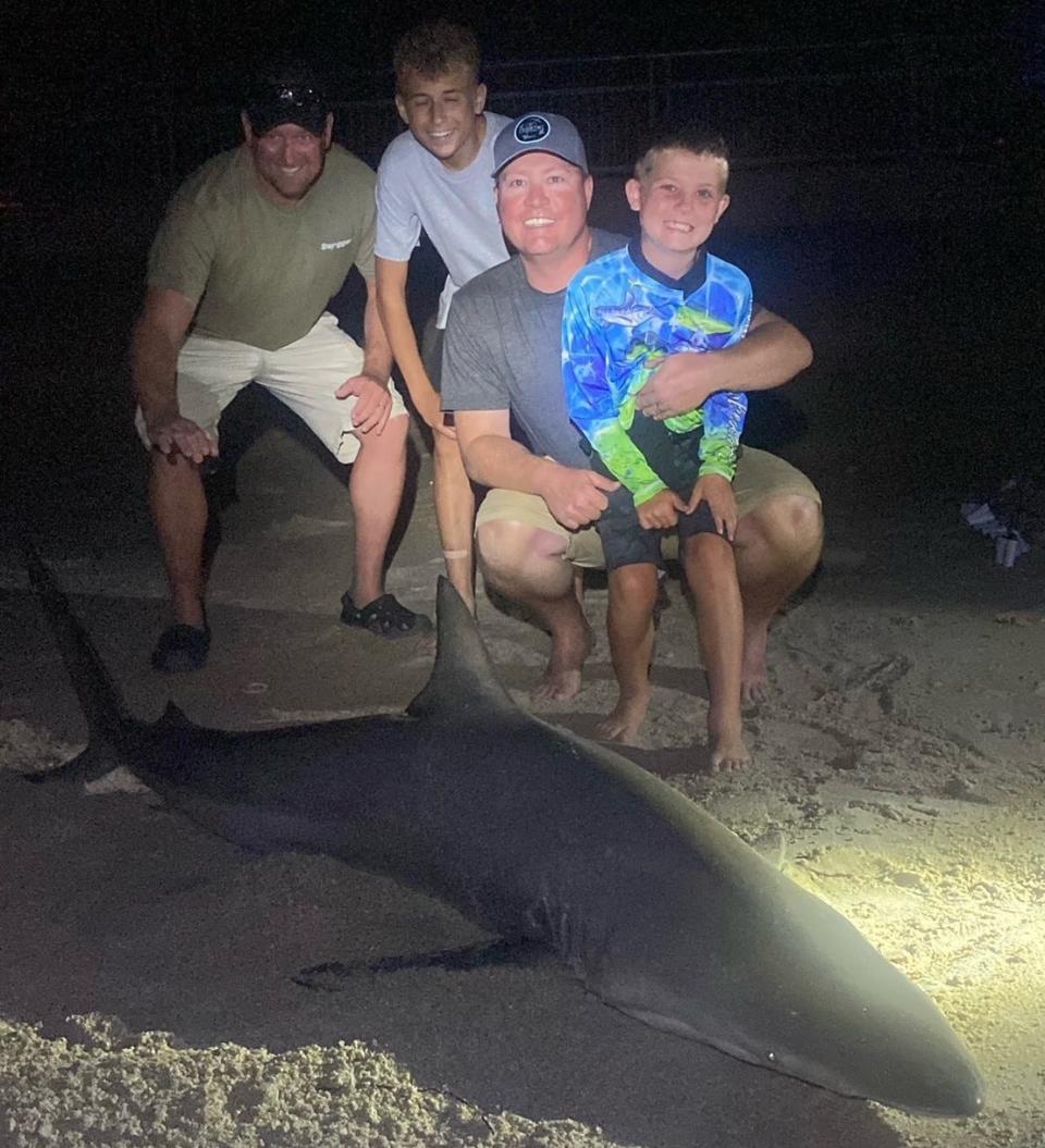 Easton (front) with dad Coye, from Kentucky, with an 89-inch, 220-pound blacktip caught with the help of NSB Shark Hunters.